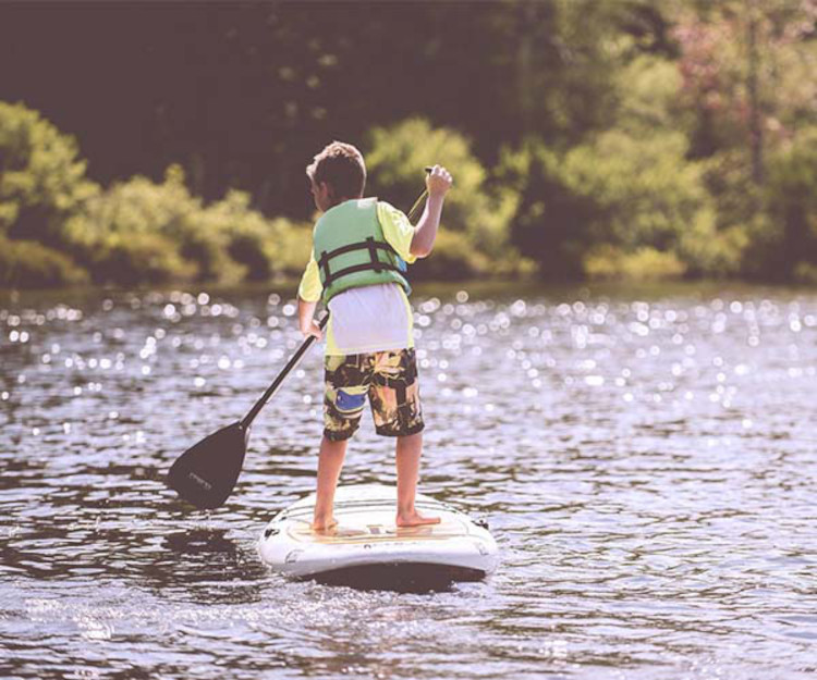 enfant en train de faire du paddle board sur un lac